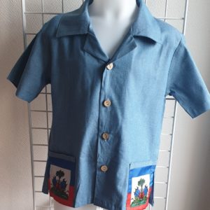 17.1 Chemise karabela tenue traditionnelle haïtienne de couleur bleue. Style ample. Deux poches latérales basses ornées chacune d'entre elles du drapeau Haïti. Cinq boutons non décoratifs centraux alignés de bas en haut de la chemise. Tissu 100% coton. Le col pouvant être surélevé selon le goût.