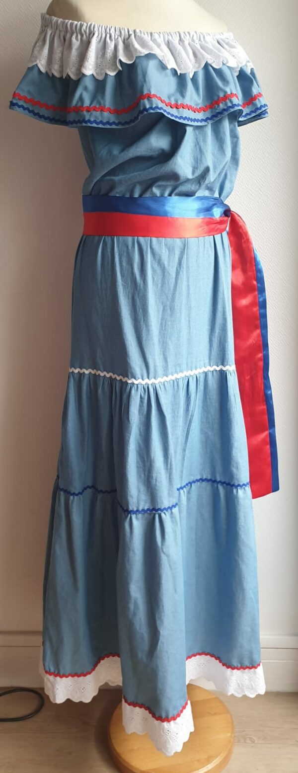 Robe carabela haïtienne longue, de couleur bleue claire et fournie avec 2 ceintures. Elastique à la taille.