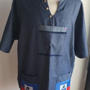 Chemise de couleur bleue foncée assortie du drapeau Haïti sur les deux des trois poches principales, sur une tenue traditionnelle. Une poche miniature supplémentaire a été autorisée sur l'une des deux manches courtes. Une série de trois petits boutons en bois clair est disposée prés le col en V. Le tissu est en carabela pur coton cent pour cent. Taille : S M L XL XXL. Prix : 79.95€ . Cette chemise est confectionnée à Paris par Anjero.