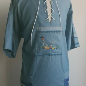 113.1Chemise bleue carabela en tenue traditionnelle haïtienne brodée à la main. Deux poches latérales, une poche brodée centrale, une mini poche sur une manche courte. Taille : S M L XL XXL. Made in Paris et confectionnée par Anjero. Prix : 94,95€