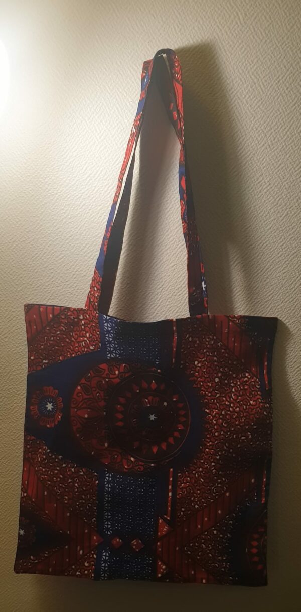 4.1Tote-bag avec d'harmonieuses figures imprimées sur un fond de couleurs bleu-rouge. Dimension 41x38. Création Anjero. Prix : 15€