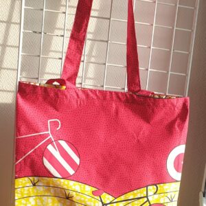 10.1Tote-bag en tissu Wax sur une décoration aux couleurs vives évoquant les jeux et les sports. Dimension : 38cm sur 41cm. Confectionné par Anjero Création. Prix : 26€.